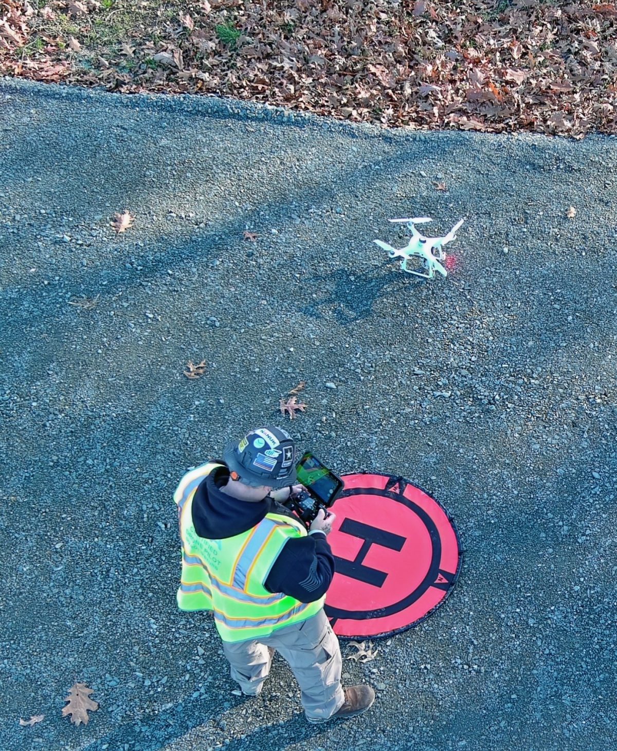 A drone pilot landing a drone on an orange landing pad marked with an "H".
