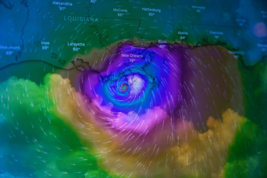 Colorful weather map showing a swirling hurricane near New Orleans, labeled with temperatures. Vibrant purple, blue, green hues.