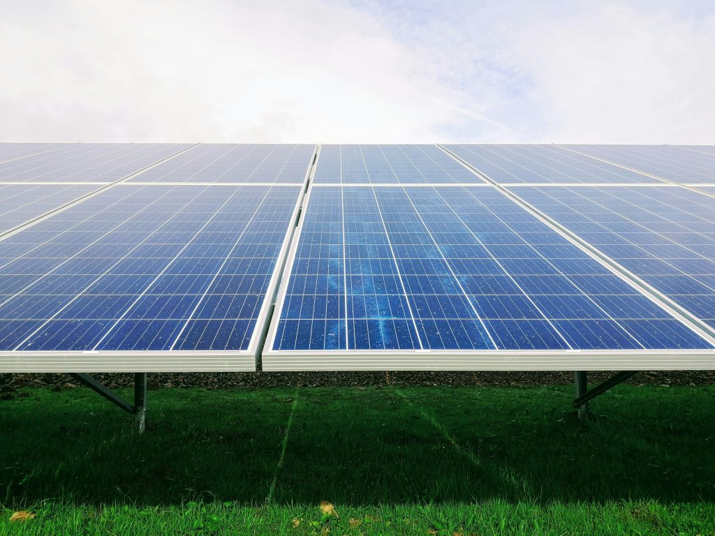 Close-up of solar panels on a green field under a partly cloudy sky, capturing a sense of clean energy and sustainability.
