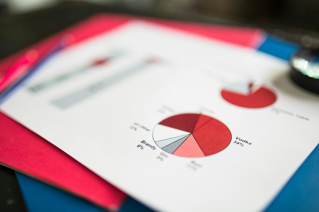 A paper with red and white pie charts and bar graphs displaying alcohol percentages on a colorful surface. The image conveys an analytical theme.